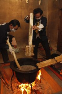 釜に入ったかゆをかき混ぜる占人＝富士吉田・小室浅間神社