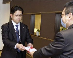 担当者に目録を手渡す松本卓士所長（左）＝甲府・山日ＹＢＳ本社