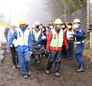 負傷者役を搬送し、登山者役を避難誘導する参加者＝富士山５合目